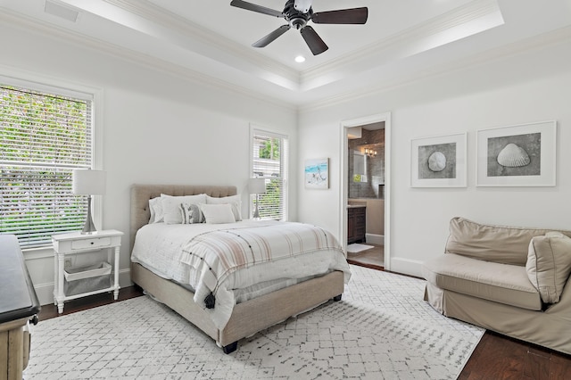 bedroom featuring baseboards, a ceiling fan, wood finished floors, a tray ceiling, and crown molding