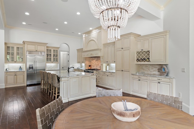 kitchen featuring cream cabinetry, custom range hood, a sink, and stainless steel built in refrigerator