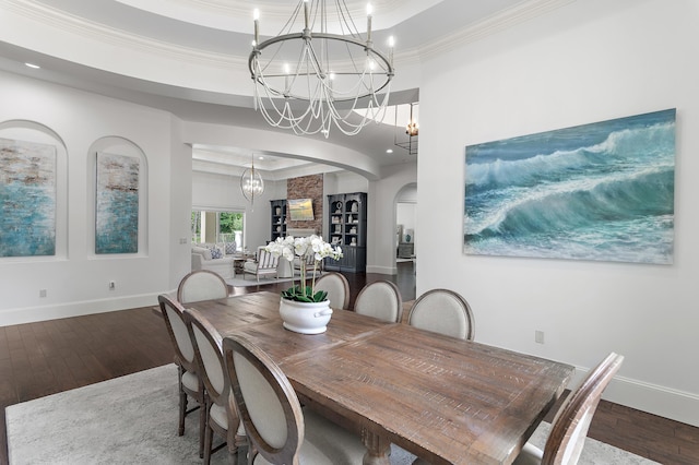 dining area with arched walkways, a raised ceiling, ornamental molding, a chandelier, and hardwood / wood-style floors