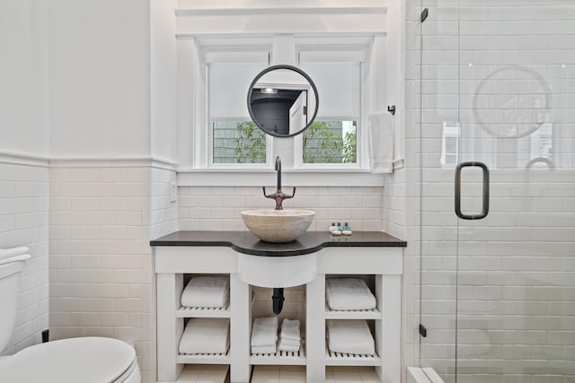 bathroom featuring a shower with shower door, sink, tile walls, toilet, and tile patterned floors