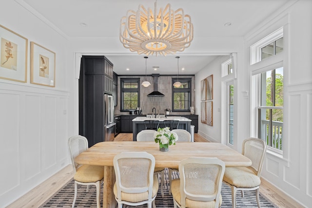 dining area featuring sink, a chandelier, and light hardwood / wood-style floors