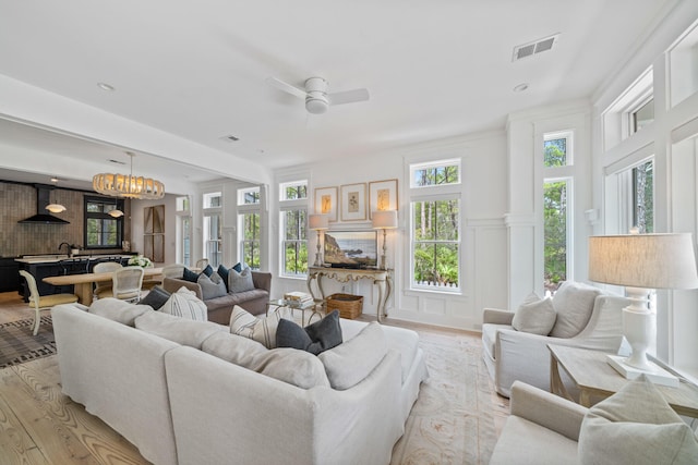 living room featuring sink, ceiling fan with notable chandelier, and light hardwood / wood-style flooring