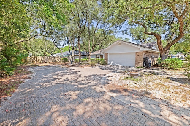 view of front facade featuring an attached garage, fence, decorative driveway, and brick siding