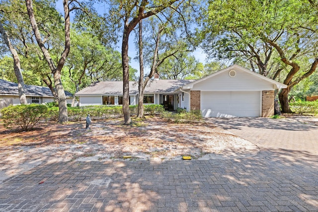 single story home featuring a garage, decorative driveway, and brick siding