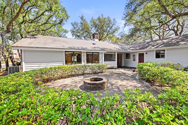 back of property with a chimney, a patio, a fire pit, and central air condition unit