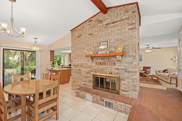 dining room with lofted ceiling with beams, light tile patterned floors, ceiling fan with notable chandelier, a fireplace, and visible vents