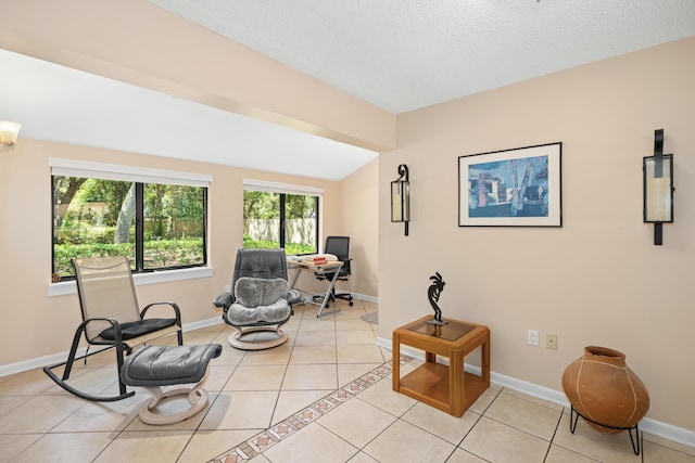 sitting room with a textured ceiling, vaulted ceiling, light tile patterned flooring, and baseboards