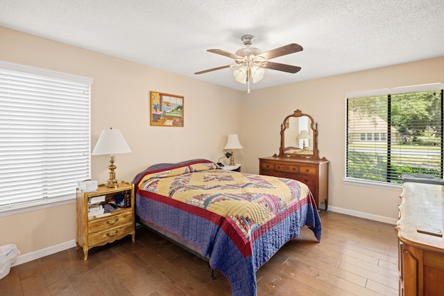 bedroom with a ceiling fan, a textured ceiling, baseboards, and dark wood-type flooring