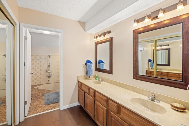 bathroom with a textured ceiling, hardwood / wood-style floors, and dual bowl vanity