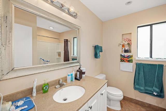 bathroom featuring a shower with shower curtain, toilet, vanity, tile patterned flooring, and baseboards