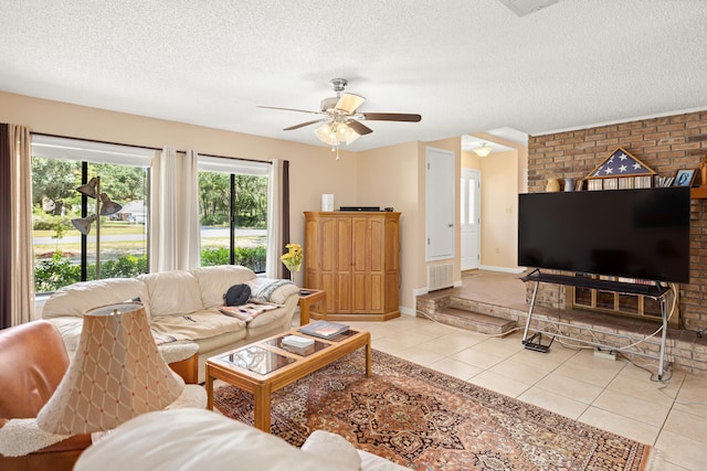 living room with ceiling fan, a textured ceiling, light tile patterned floors, and brick wall