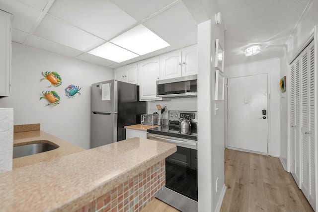 kitchen featuring appliances with stainless steel finishes, light hardwood / wood-style floors, and white cabinetry