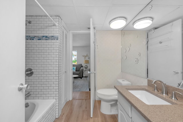 full bathroom with wood-type flooring, tiled shower / bath combo, vanity, and toilet