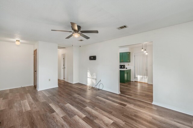 unfurnished room with ceiling fan, a textured ceiling, and dark wood-type flooring