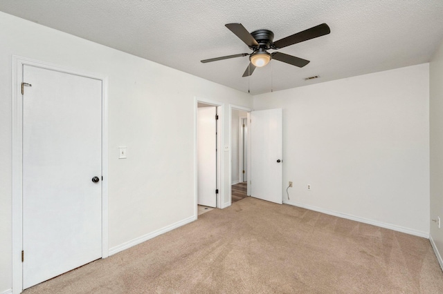 unfurnished bedroom featuring ceiling fan, a textured ceiling, and light carpet