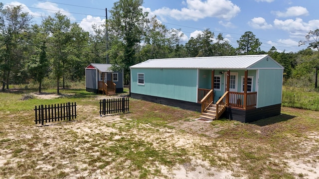 view of front of property featuring a porch and a storage shed