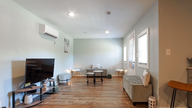 living area featuring a wall unit AC and light wood-type flooring