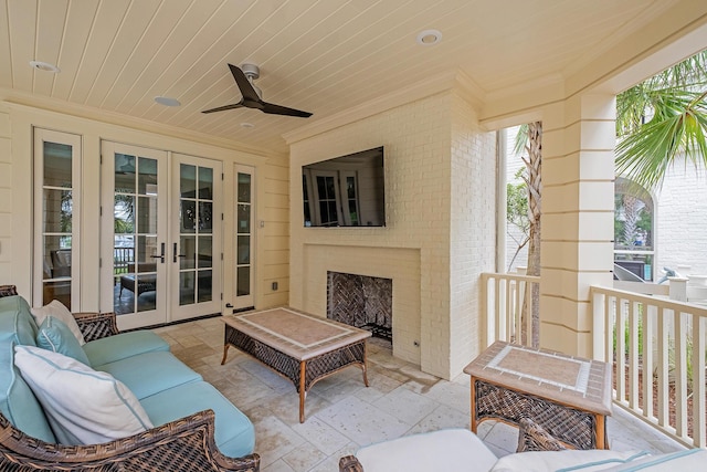 view of patio / terrace with a ceiling fan, an outdoor living space with a fireplace, and french doors