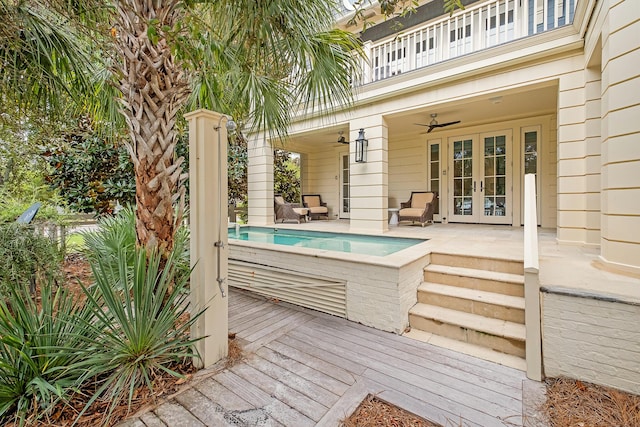 wooden deck with an outdoor pool, french doors, and ceiling fan