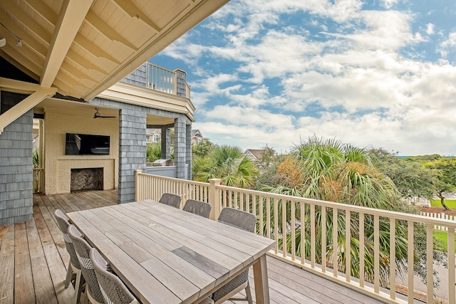 wooden deck featuring outdoor dining space and a ceiling fan