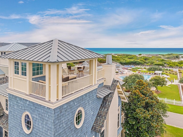 view of home's exterior featuring metal roof, a water view, a balcony, and a standing seam roof