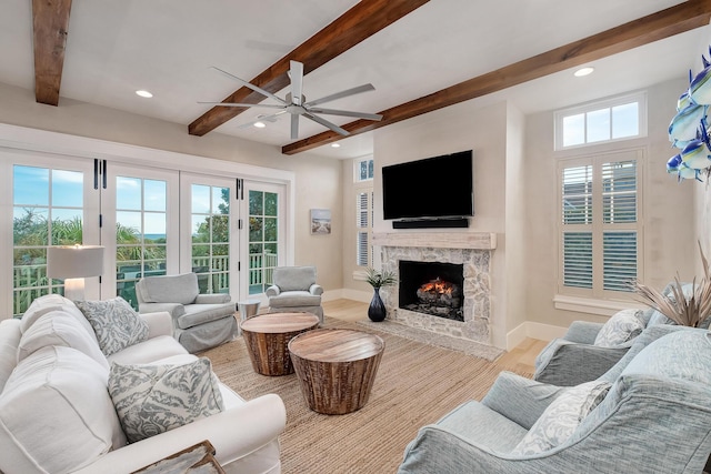 living area with a wealth of natural light, baseboards, a fireplace with flush hearth, and wood finished floors