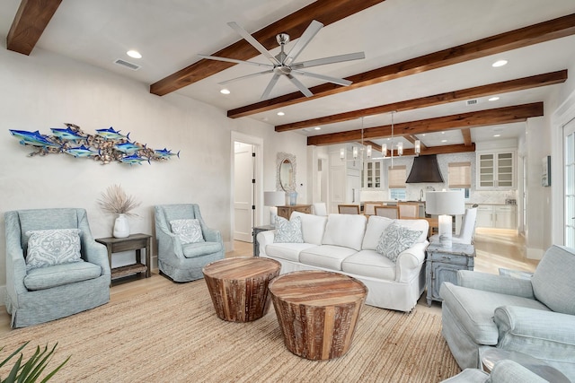 living area with a ceiling fan, visible vents, light wood-style flooring, recessed lighting, and beamed ceiling