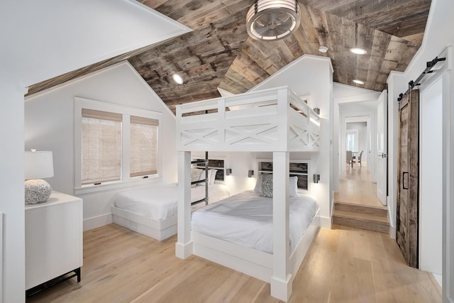 bedroom with wood finished floors, baseboards, lofted ceiling, wood ceiling, and a barn door