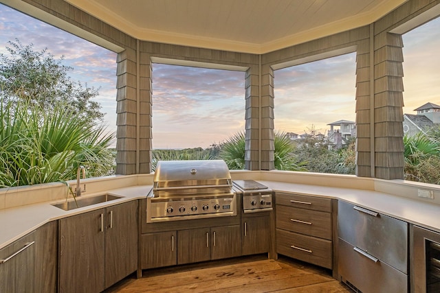 patio terrace at dusk featuring grilling area, an outdoor kitchen, and a sink