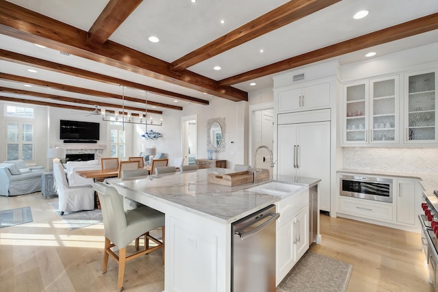 kitchen featuring a sink, a kitchen breakfast bar, white cabinets, a fireplace, and dishwasher