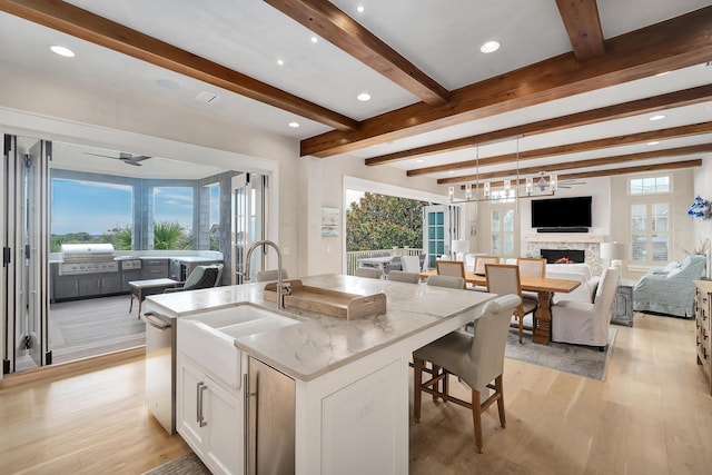 kitchen with a wealth of natural light, open floor plan, a lit fireplace, and a sink