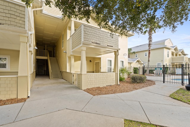 townhome / multi-family property with a balcony, fence, and stairway