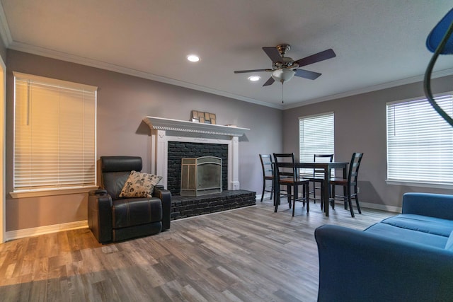 living room featuring hardwood / wood-style flooring, ornamental molding, a fireplace, and ceiling fan