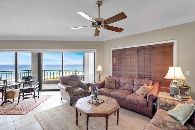 living room featuring a water view, a healthy amount of sunlight, light tile patterned floors, and a textured ceiling