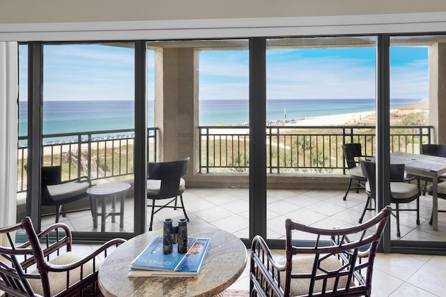 sunroom / solarium with a water view, a healthy amount of sunlight, and a view of the beach