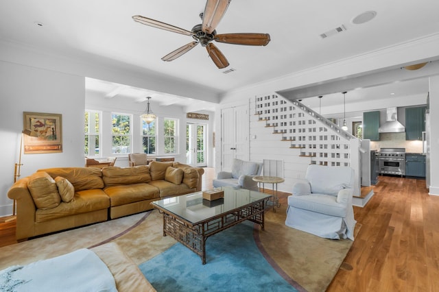 living room featuring light wood-type flooring, ceiling fan, crown molding, and beamed ceiling