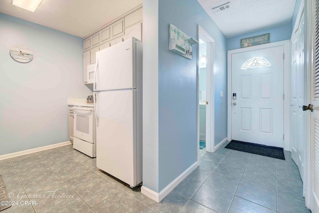 foyer entrance featuring a textured ceiling and light tile patterned floors