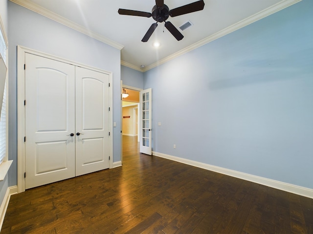 unfurnished bedroom with dark wood-style floors, crown molding, a closet, visible vents, and baseboards