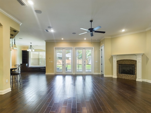 unfurnished living room featuring crown molding, dark hardwood / wood-style flooring, a fireplace, and ceiling fan with notable chandelier