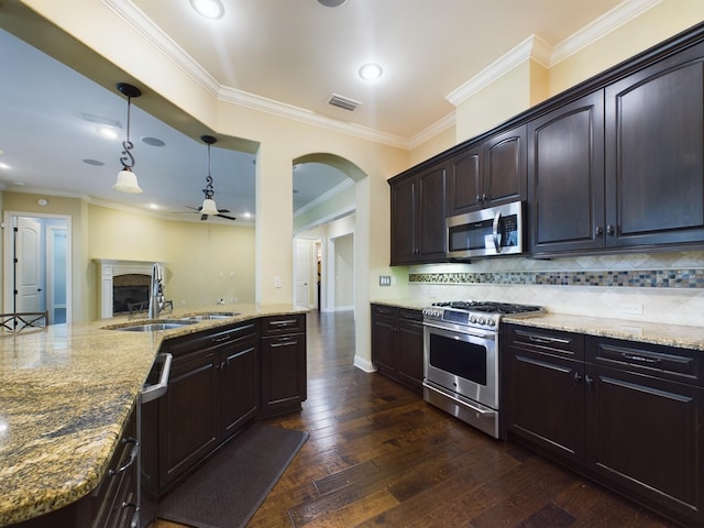 kitchen featuring light stone counters, appliances with stainless steel finishes, dark wood-type flooring, decorative light fixtures, and backsplash