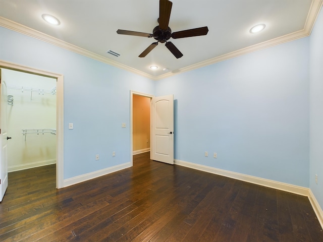 unfurnished bedroom featuring crown molding, a spacious closet, a closet, ceiling fan, and hardwood / wood-style floors