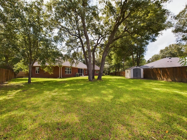 view of yard featuring a fenced backyard, an outdoor structure, and a storage shed