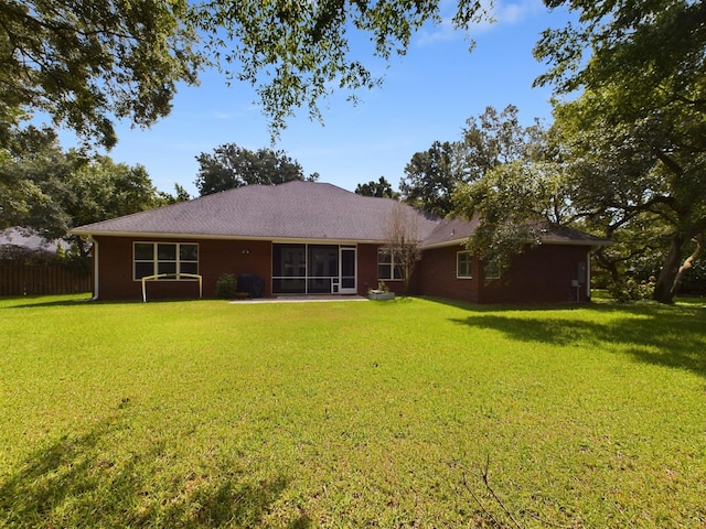 rear view of house featuring a lawn and a sunroom