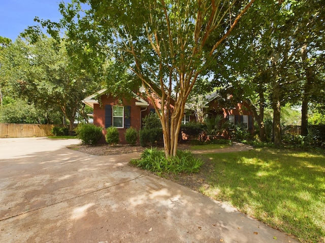 view of front of property with brick siding, a front yard, and fence