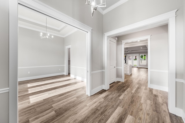 hallway featuring hardwood / wood-style flooring, crown molding, and a notable chandelier