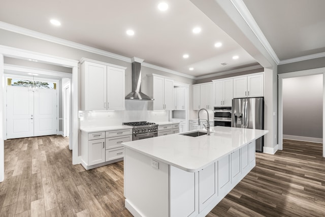 kitchen featuring appliances with stainless steel finishes, wall chimney exhaust hood, white cabinetry, and sink