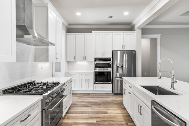 kitchen with wall chimney exhaust hood, sink, stainless steel appliances, light stone countertops, and white cabinets