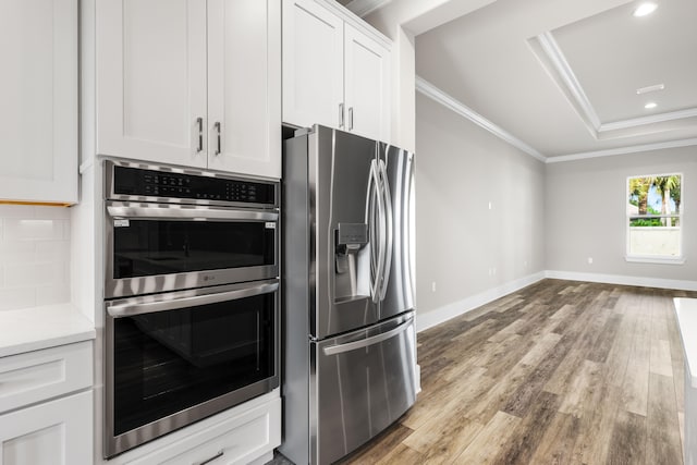 kitchen featuring light wood-type flooring, decorative backsplash, white cabinets, crown molding, and appliances with stainless steel finishes