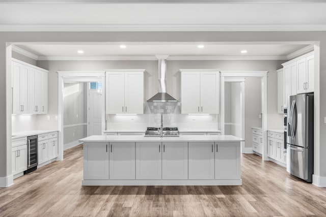 kitchen with beverage cooler, white cabinets, stainless steel refrigerator with ice dispenser, and a kitchen island with sink