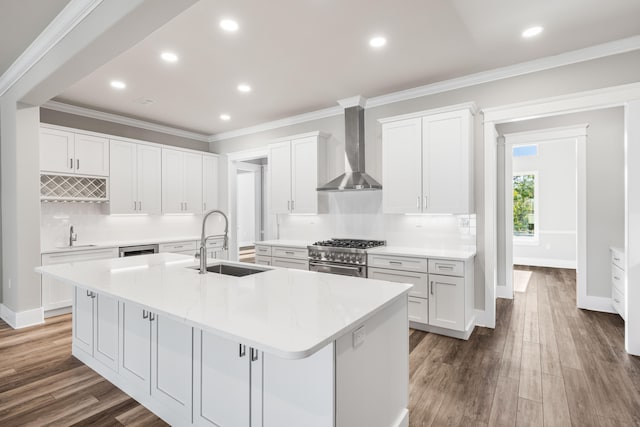 kitchen featuring wall chimney range hood, high end stove, sink, white cabinets, and a large island